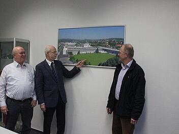 Die Brüder Michael, Johannes und Georg Weber (von links) vor einem Foto des Werks II in der Industriestraße in Kronach. Johannes Weber zeigt auf das Areal, auf dem der Neubau entstehen soll.  Foto: Friedwald Schedel
