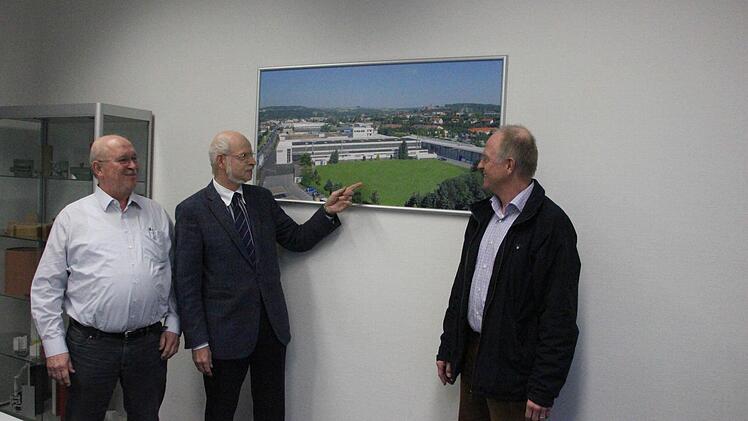 Die Brüder Michael, Johannes und Georg Weber (von links) vor einem Foto des Werks II in der Industriestraße in Kronach. Johannes Weber zeigt auf das Areal, auf dem der Neubau entstehen soll.  Foto: Friedwald Schedel