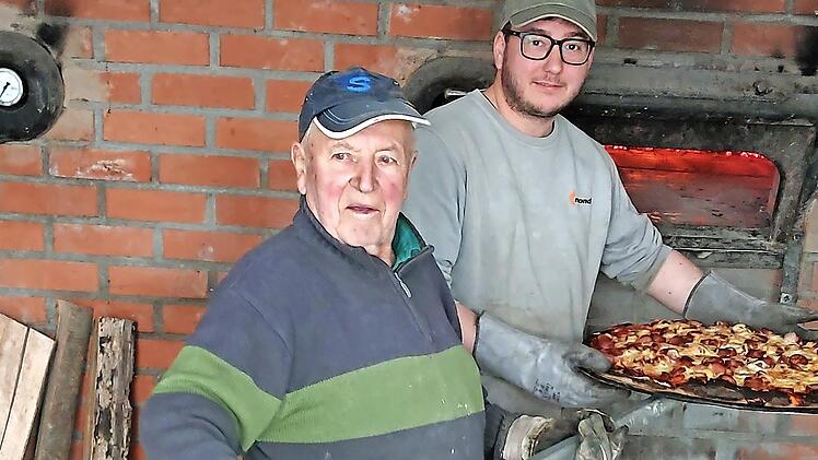 Edgar Warmuth und Marcel Kraus holen die frische Pizza aus dem Backofen
