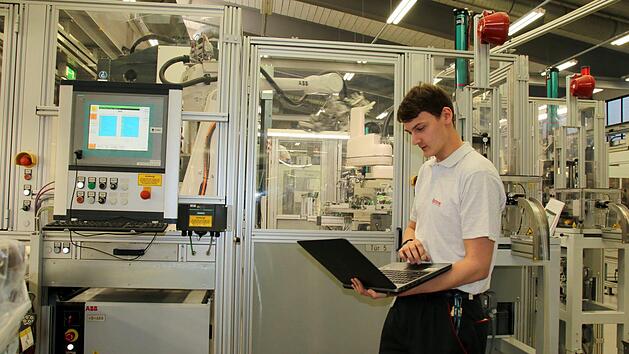 Bei Brose kann Nicolas Sch&ouml;nm&uuml;ller sein handwerkliches Geschick mit seiner Begeisterung f&uuml;rs Programmieren verbinden. Seine Pr&uuml;fung zum Elektroniker f&uuml;r Automatisierungstechnik legte er mit der Note 1,2 ab und erreichte damit in der Winterpr&uuml;fung 2016/17 das beste Ergebnis von 302 Absolventen. Fehler auszulesen, wie hier an einer Brose-Kunststoffspritzgussanlage, geh&ouml;rt zu seinen Aufgaben.  Foto: Bettina Knauth