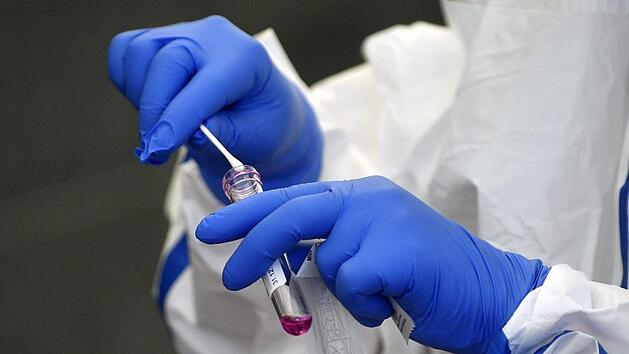 Corona-Test: Eine Helferin steckt einen Tupfer mit dem Rachenabstrich  in ein Röhrchen.Foto: Hendrik Schmidt/dpa