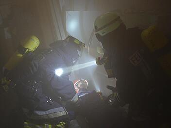 Die Atemschutzgeräteträger müssen bei der Großübung des Marktes Burkardroth aus der Werkstatt Verletzte bergen. Hier haben sie Marvin Höchemer von der Jugendfeuerwehr gefunden, der als Statist einen verunglückten Arbeiter darstellte. Foto: Kathrin Kupka-Hahn
