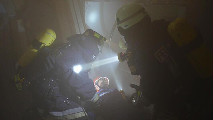 Die Atemschutzgeräteträger müssen bei der Großübung des Marktes Burkardroth aus der Werkstatt Verletzte bergen. Hier haben sie Marvin Höchemer von der Jugendfeuerwehr gefunden, der als Statist einen verunglückten Arbeiter darstellte. Foto: Kathrin Kupka-Hahn