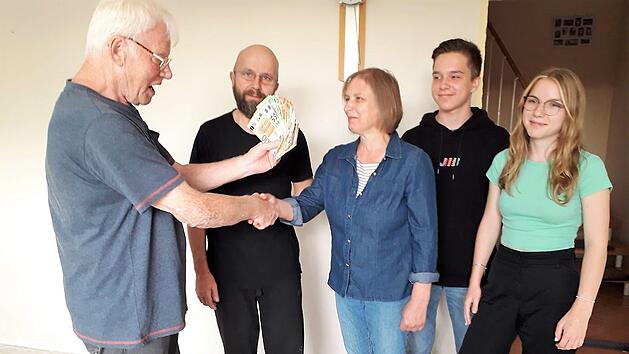 Manfred Ringelmann (links) übergibt die Spende seines Heimatvereins an eine von der Flutkatastrophe betroffene Familie.