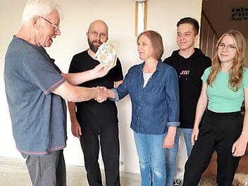 Manfred Ringelmann (links) übergibt die Spende seines Heimatvereins an eine von der Flutkatastrophe betroffene Familie.