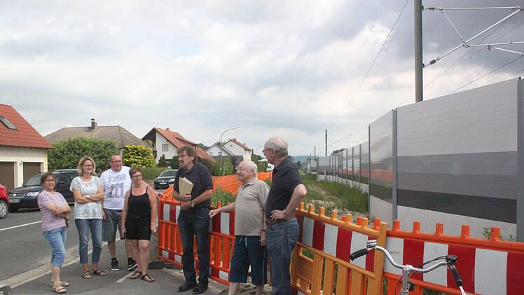 Rechtsanwalt Johann Bramann (Dritter von rechts) trifft sich mit den Geschädigten vor Ort, um das weitere Vorgehen zu besprechen; im Hintergrund die Lärmschutzwand und die Häuser der Betroffenen. Foto: Matthias Einwag