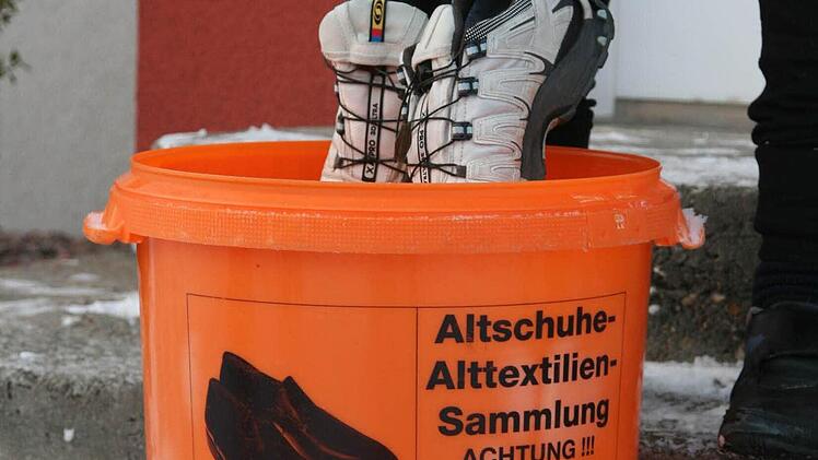 Ein Junge wirft seine abgetragenen Turnschuhe in einen der Sammeleimer.  Foto: Daniela Röllinger