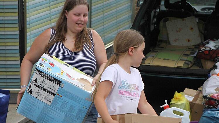 Cecilia Rüttiger, die jüngste Helferin, und ihre Schwester Rebecca tragen Kartons zum Lkw. Fotos: T. Dill