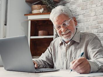 Älterer Fernarbeiter. Konzentrierte ältere männliche Person mit Brille. Arbeit am Laptop von zu Hause. Alter Mann Mitarbeiter. Home Office. Arbeiten trotz Rente.