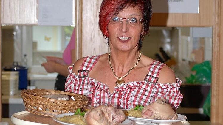 Lizi Maier serviert Schweinshaxen - ein freundliches Lächeln für die Gäste der Willmersreuther "Krumba" gibt es gratis. Foto: Karl Klippel