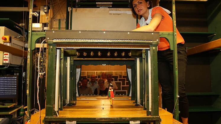 Der ungewöhnlicher Blick durch die Kulissen zeigt die winzige Bühne des Bamberger Marionettentheaters mit dessen Leiterin Maria Sebald. Im Hintergrund sind einige Zuschauer zu erkennen. Foto: Barbara Herbst