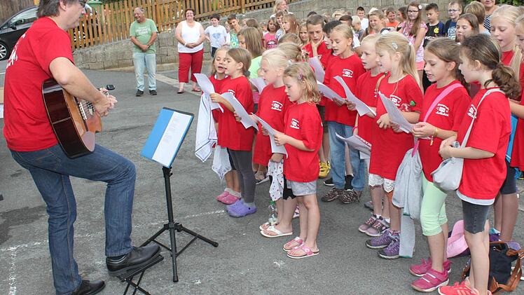 Die Roth-Kehlchen mit Chorleiter Stefan Kriegel an der Gitarre singen im Schulhof. Foto: Gerd Klemenz
