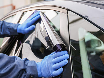Männlicher Arbeiter, der Autoscheiben tönt