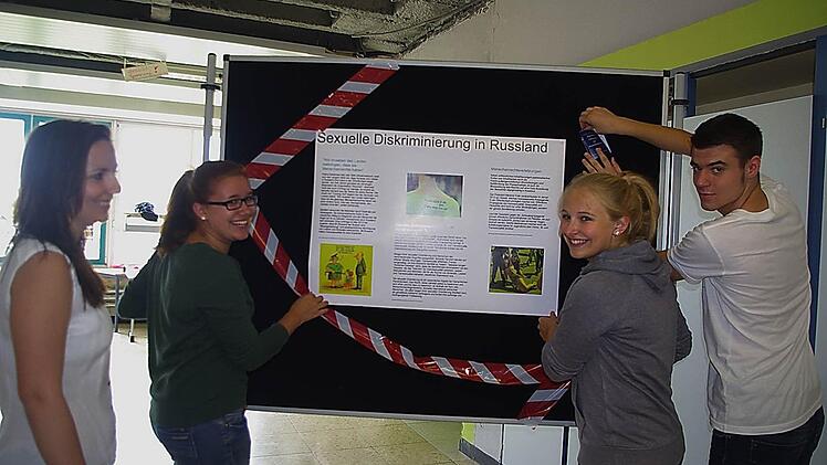Sozialkundelehrerin Franziska Gröger betrachtet die Stellwand, die von Sophia Rubel und Pauline Wittig zum Thema "Sexuelle Diskriminierung" gestaltet wird. Auch Benedict Behner (rechts) hilft mit.  Foto: Heike Schülein