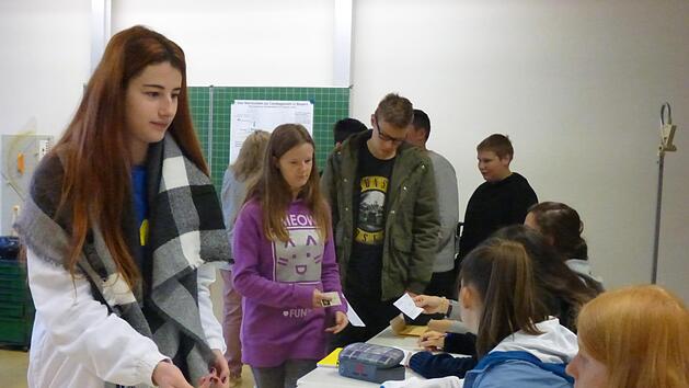 Wie bei der richtigen Wahl zum bayerischen Landtag zeigt Viviane Schwartl vor Aush&auml;ndigung der identischen Wahlunterlagen f&uuml;r den Stimmkreis Bad Kissingen ihren Personalausweis vor, bevor ihr die Unterlagen ausgeh&auml;ndigt werden. Celina Schmidt, Lukas G&ouml;tz und Leon Ge&szlig;ner warten noch auf ihre Wahlscheine, Sophie B&auml;umker (vorne rechts) fungiert als Wahlhelferin. Foto: Manfred Mellenthin