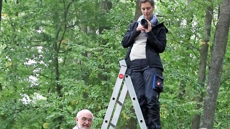 Grabungsingenieurin Britta Ziegler fotografiert die Grabungsstelle, die Helfer Claus Schaffranek und Julia Stiene stützen die Leiter.