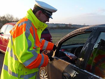 Der Verkehrsexperte der Polizei, Stefan Scherrer, übergibt einer Autofahrerin das Faltblatt zum Thema Wildunfälle. Das tat er am gestrigen Donnerstagmorgen auf der Straße zwischen Oberhohenried und Königsberg. Die Strecke ist bekannt für viele Wildunfälle.  Foto: Klaus Schmitt