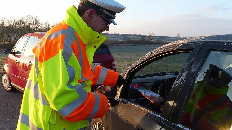 Der Verkehrsexperte der Polizei, Stefan Scherrer, übergibt einer Autofahrerin das Faltblatt zum Thema Wildunfälle. Das tat er am gestrigen Donnerstagmorgen auf der Straße zwischen Oberhohenried und Königsberg. Die Strecke ist bekannt für viele Wildunfälle.  Foto: Klaus Schmitt