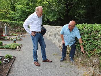 Efeu schädigt Teile der Friedhofsmauer in Burghausen. Friedhofsreferent Klaus Schebler zeigt Bürgermeister Helmut Blank, wo es Probleme gibt. Im Hintergrund ein sanierter Bereich der Friedhofsmauer.Heike Beudert