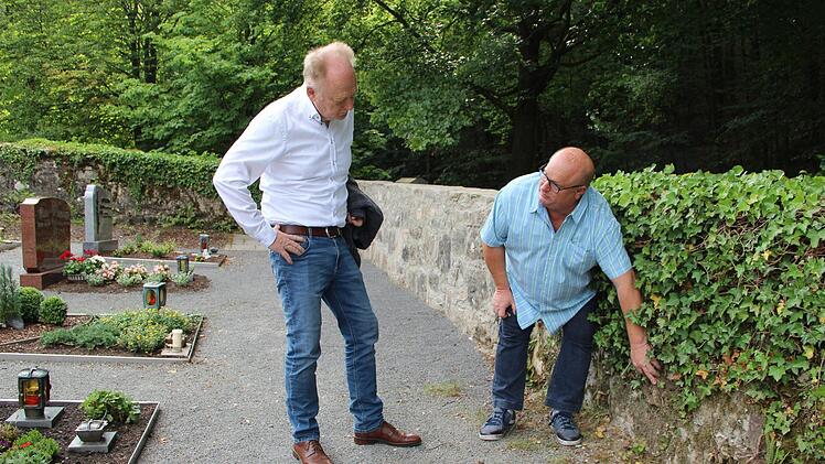 Efeu schädigt Teile der Friedhofsmauer in Burghausen. Friedhofsreferent Klaus Schebler zeigt Bürgermeister Helmut Blank, wo es Probleme gibt. Im Hintergrund ein sanierter Bereich der Friedhofsmauer.Heike Beudert