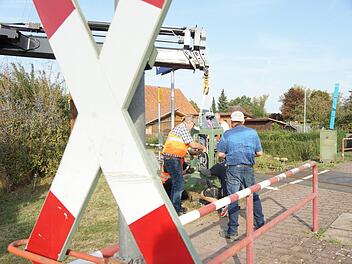 Arbeiter schließen den neuen Antriebskasten für die Fußgängerschranke an die Steuerleitung. Foto: Arkadius Guzy