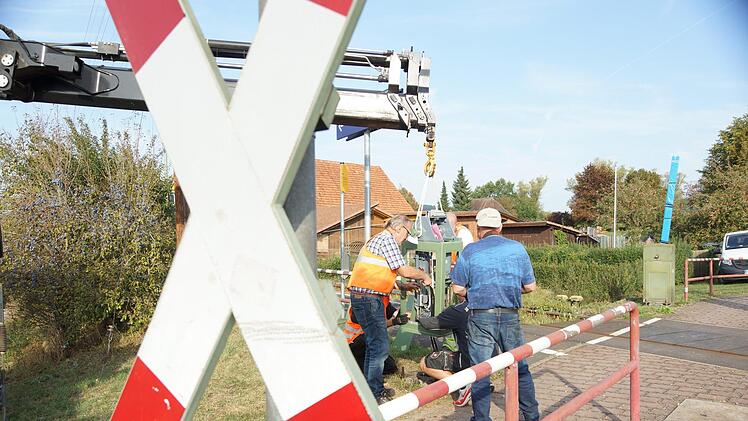 Arbeiter schließen den neuen Antriebskasten für die Fußgängerschranke an die Steuerleitung. Foto: Arkadius Guzy