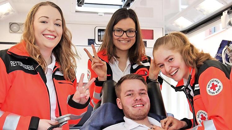 Daniel Genslein als "Hahn im Korb": Für das Symbolfoto hat sich der Rettungsdiensthelfer, der sich ehrenamtlich beim BRK im Rettungsdienst engagiert, selbst einmal auf die Trage im Rettungswagen gelegt. Die "Bufdis" (von links) Sara Klopf, Sophia Haase und Katrin Habermann blicken voller Freude auf ihre Zeit im Freiwilligendienst beim BRK-Rettungsdienst. Foto: Michael Will