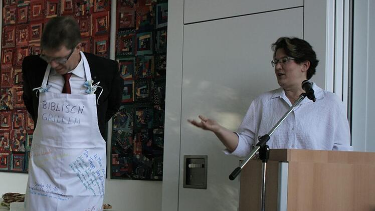 Die biblische Anweisung zum Grillen steht auf der Sch&uuml;rze. Alina Ellgring hatte ein originelles Geschenk f&uuml;r Pfarrer Gundermann dabei. Foto: Maria L&ouml;ffler