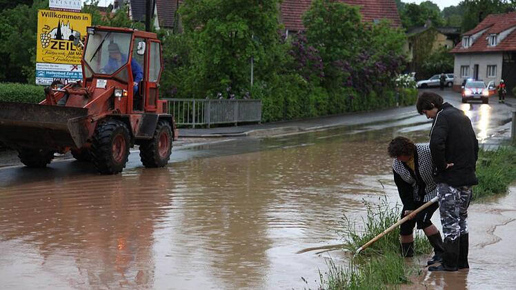 Anwohner versuchen in Krum einen Gully zu reinigen, um den Wasserabfluss zu ermöglichen.