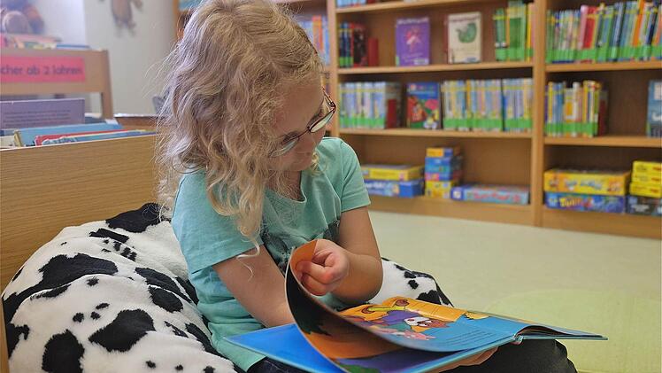 Michelle hat es sich in der neuen Bücherei gemütlich gemacht und schaut sich gleich vor Ort ein Buch an. Foto: Gerd Schaar