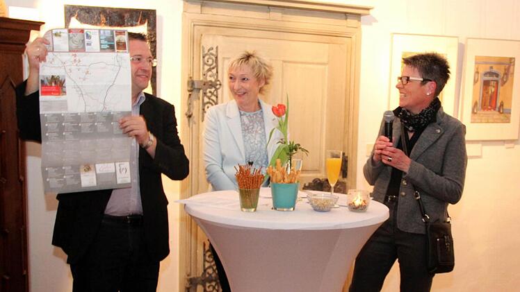 Bürgermeister Fischkal zeigt die Rückseite der Kunstkarte, daneben Siggi Wolt und Jutta Köhler. Fotos: Blum
