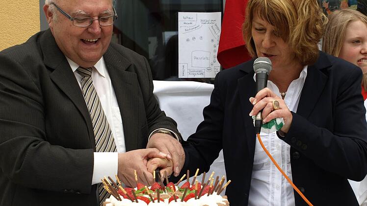 Bürgermeister Siegfried Erhard (links) und Rektorin Sonja Then schneiden eine Jubiläumstorte an.
