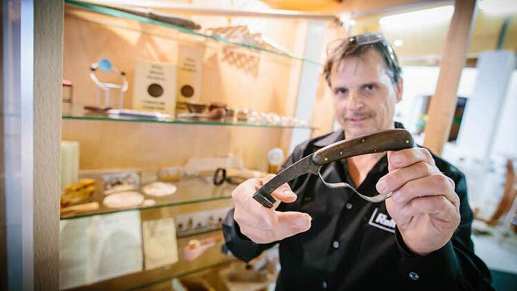 Leo Rottmann zeigt ein antikes Werkzeug aus einem Schrank mit Andenken an die Anfänge der Firma.