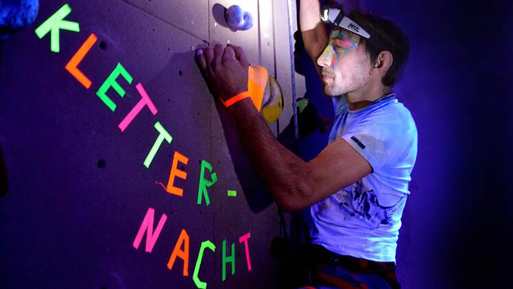 Wie farbige Sterne am Nachthimmel leuchten die Klettergriffe bei Schwarzlicht: Im Bild klettert Andreas Grau , Mitorganisator der Kletternacht in der Bad Kissinger Kletterhalle. Fotos: Peter Rauch