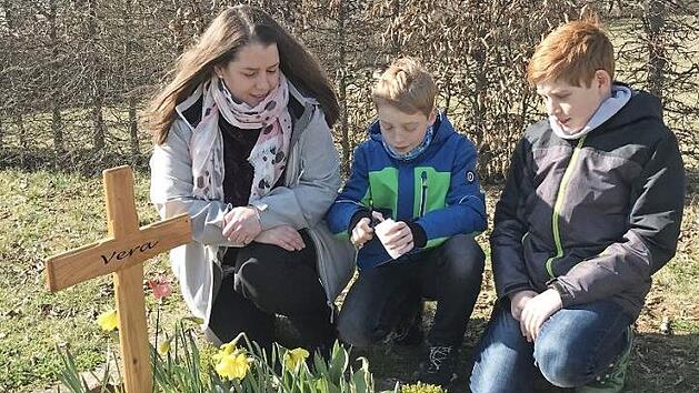 Anja Lemberger mit ihren Kindern am Erdurnengrab ihrer m Oktober 2018 in der 20. Schwangerschaftswoche still geborenen Tochter Vera  Foto: epd