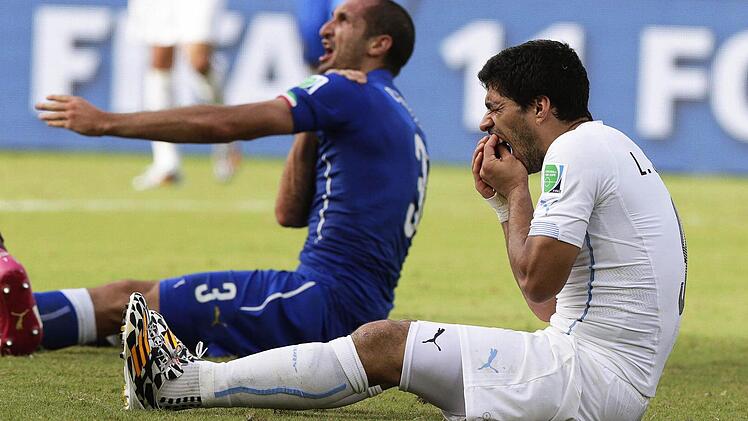 Fußball-Profi Giorgio Chiellini (l) aus Italien beschwert sich, von Luis Suarez aus Uruguay (r) gebissen worden zu sein. Foto: dpa