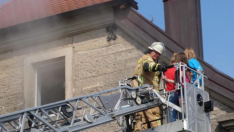 Drei M&auml;dchen werden im Korb der Drehleiter in Sicherheit gebracht. Foto: Christian Licha