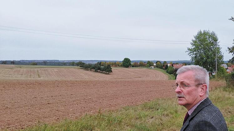 Oberthulbas Bürgermeister Gotthard Schlereth vor der als Bauland denkbaren Ackerfläche mit Baumreihe.Sigismund von Dobschütz