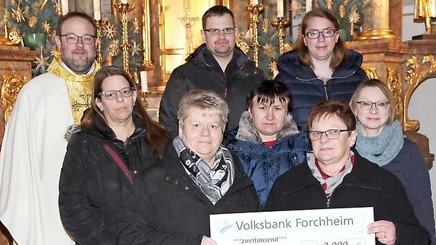Pfarrgemeinderatsvorsitzende Margitta Bastian (vorne, rechts) &uuml;bergibt den Spendenscheck an Elisabeth Roith (vorne, links) f&uuml;r den Verein "Hilfe f&uuml;r Anja". Mit auf dem Bild sind Mitglieder des Pfarrgemeinderates und Pfarrer Daniel Schuster. Foto: Mathias Erlwein