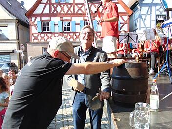 Bürgermeister Heinz Richter schwingt den Holzhammer zum Bieranstich - ein Helfer hält das Fass. Fotos:  Petra Malbrich