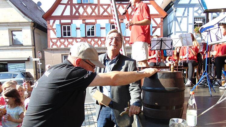 Bürgermeister Heinz Richter schwingt den Holzhammer zum Bieranstich - ein Helfer hält das Fass. Fotos:  Petra Malbrich