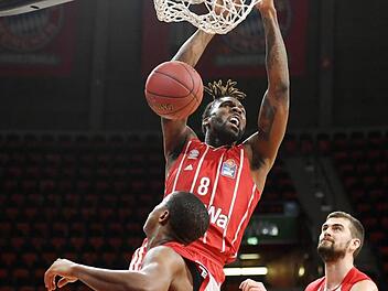 Jalen Reynolds beim Dunking gegen die Bamberger Devon Hall (vorne) und David Kravish. Der Bayern-Center war mit 17 Punkten bester Werfer der Partie.  Foto: Tobias Hase/dpa