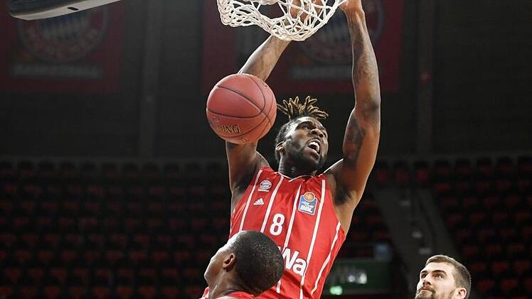 Jalen Reynolds beim Dunking gegen die Bamberger Devon Hall (vorne) und David Kravish. Der Bayern-Center war mit 17 Punkten bester Werfer der Partie.  Foto: Tobias Hase/dpa