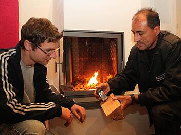 Bezirkskaminkehrermeister Hilmar Stadter (rechts) nimmt bei einem Kunden die Feuerstelle unter die Lupe und zeigt, wie man die Restfeuchte von Holz bestimmt. Foto: Archiv