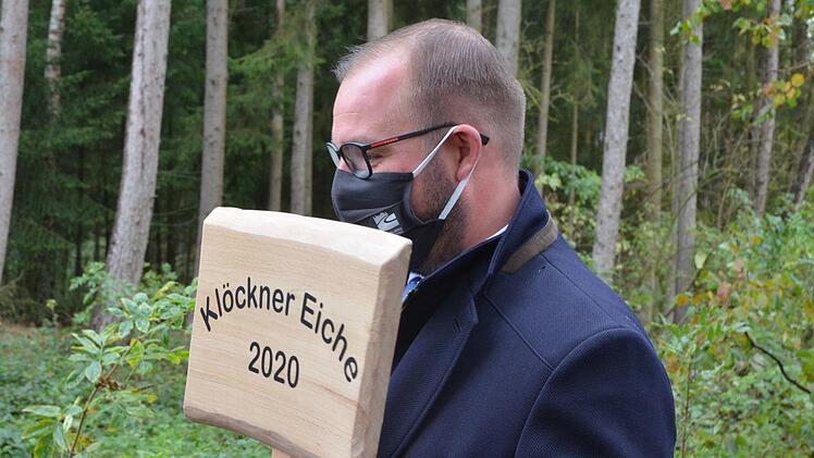 Landrat Sebastian Straubel hält das Schild zur Baumpflanzung.