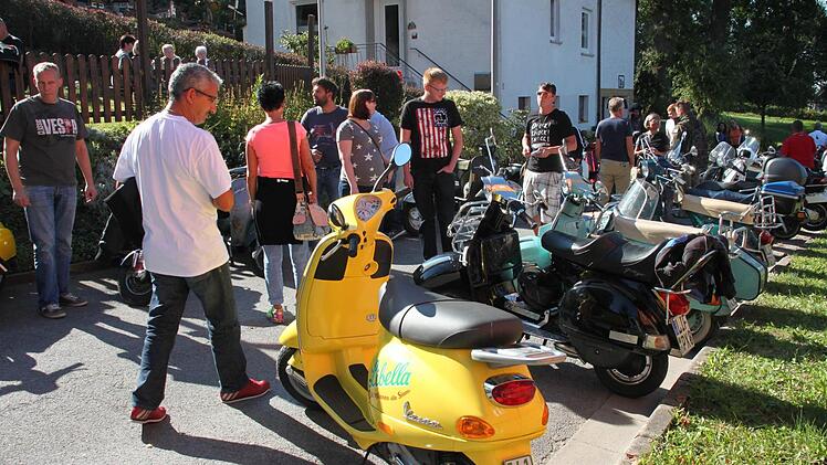 Das Chrom der Vespas glänzt mit der Spätsommersonne um die Wette. Groß und Klein flanieren in Maineck an den alten und neuen Rollern vorbei, die sich wie Perlen an einer Schnur am Bergweg aneinanderreihen. Foto: Stephan Stöckel.