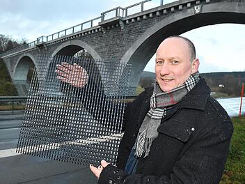 Roy Thyroff zeigt an der ehemaligen Bahnbrücke bei Naila ein Carbon-Gitter. Der Beton der Gewölbebögen wurde 2016 mit Carbonbeton instandgesetzt. Foto: Ronald Rinklef
