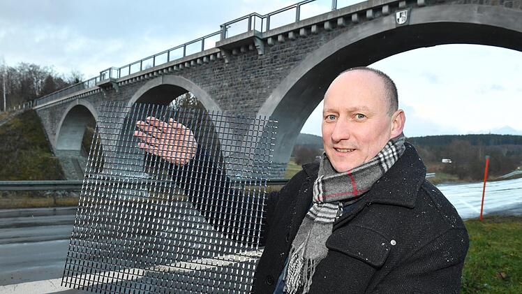 Roy Thyroff zeigt an der ehemaligen Bahnbrücke bei Naila ein Carbon-Gitter. Der Beton der Gewölbebögen wurde 2016 mit Carbonbeton instandgesetzt. Foto: Ronald Rinklef