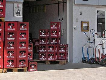 Im Bild sind gestapelte Bierk&auml;sten der Familienbrauerei Hennemann vor einem Geb&auml;ude zu sehen. Daneben stehen Handwagen. Die Brauerei ist in Sambach ans&auml;ssig.