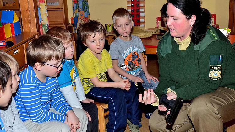 Aufmerksam beobachten die Kinder, wie Polizeihauptmeisterin Heike Benker das Magazin aus der Pistole nimmt. Fotos: Dieter Hübner
